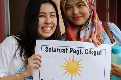 Facilitator and teacher holding a good morning sign