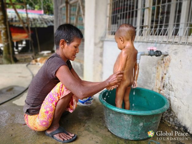IMG_20180517_115431 (1)-min A grandmother bathing her grandson with filtered water. All the children in the village now bathe three times a day on average with clean water, reducing the occurrence of skin disease and fevers