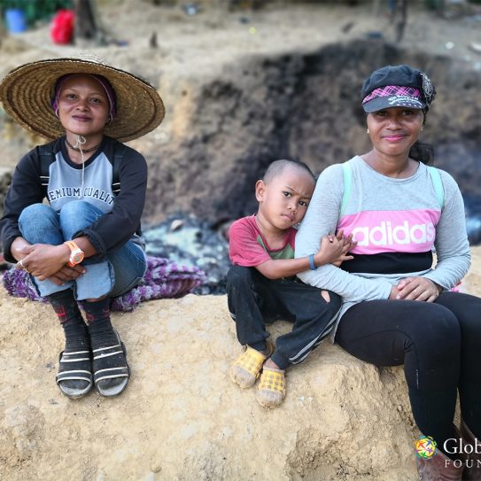Women sitting by a pit where plastic waste was being burnt.
